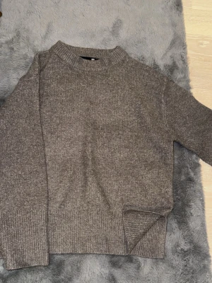 stickad tröja  - Mysig grå/brun stickad tröja. Tröjan har en rak passform och är tillverkad i ett mjukt material som känns skönt mot huden. Perfekt för kyliga dagar och enkel att matcha med olika outfits.