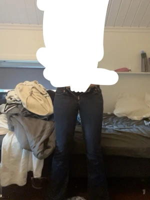 Mörkblå bootcut jeans - Säljer ett par mörkblå bootcut jeans med klassisk femficksdesign och hög midja. Jeansen har en snygg passform som sitter tajt över låren och släpper ut nedtill. Perfekta till sneakers eller boots! Är lite slitna där ner till.