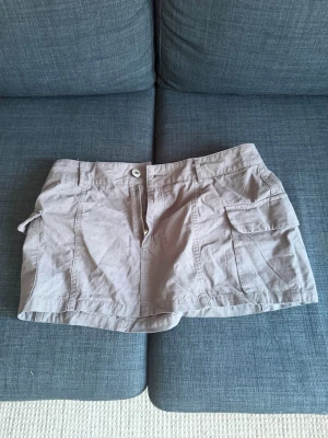 Beige utility skort med fickor - Snygg beige skort med utility-vibe, har stora sidofickor och knappstängning fram. Tillverkad i ett lätt bomullsmaterial som känns bekvämt och luftigt. Perfekt för dig som gillar en avslappnad men ändå trendig stil.