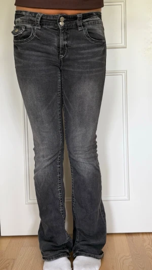 Grå bootcut jeans - Snygga grå bootcut jeans med lätt slitna detaljer och kontrastsömmar. Jeansen har femfickor, normal midja och är tillverkade i ett stretchigt denimtyg som sitter bekvämt. Perfekta för en avslappnad och trendig look.