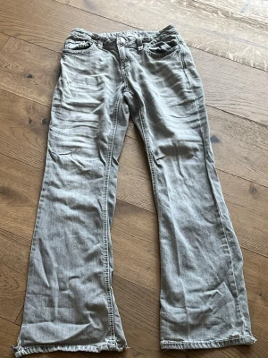 Gråa bootcut jeans med söndrig kant nertill - Säljer ett par ljusgrå bootcut jeans med  söntrig ,  kant nedtill. Jeansen har klassisk femficksmodell och är tillverkade i ett mjukt denimtyg. Perfekta för en avslappnad och trendig look.