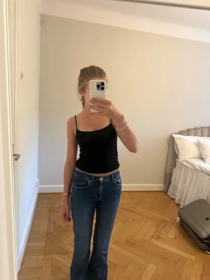 Blå bootcut jeans med hög midja - Säljer ett par blå bootcut jeans med hög midja och utsvängda ben. Jeansen har klassisk femficksdesign, bälteshällor och stängs med knapp och dragkedja. Materialet är denim i bomull och färgen är en snygg mellanblå tvätt. (Waist S length 31)