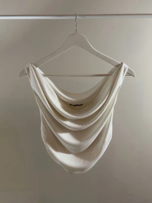 Vit draperad ärmlös linnetopp - Säljer en stilren vit linnetopp med draperad front och rygg.
