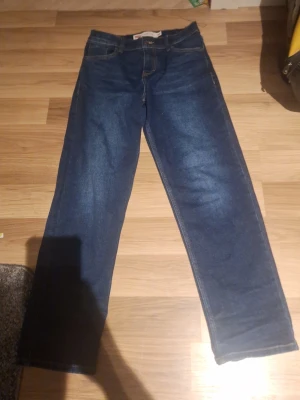 Helt oanvända Mörkblå raka jeans från Levi's - Säljer ett par hekt nya (oanvända)klassiska mörkblå jeans från Levi's med raka ben och snygga kontrastsömmar. Jeansen har fem fickor och den ikoniska Levi's-detaljen på bakfickan. Perfekta till din vardagsstil!