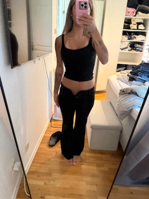 Svarta low waist jeans - Säljer ett par svarta jeans med låg midja och unik v-formad skärning framtill. Jeansen har utsvängda ben och klassisk femficksmodell. Materialet är denim och passformen är tight upptill med mer vid nedtill för en trendig siluett. Byxorna är fromma weekday och är i modellen Nova low Rise slim bootcut. För små på mig därav så kan jag inte knäppa de w25L30