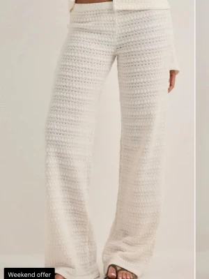 Nelly set  - Mysigt vitt stickat loungewear-set med vida byxor och matchande topp. Setet har ett luftigt virkat mönster och är tillverkat i mjukt material. Perfekt för chill dagar hemma eller när du vill vara bekvämt klädd men ändå se snygg ut. Endast använt en gång så väldigt bra skick. Byxorna är i stl S och tröjan i Xxs. Kontakta mig vid fler bilder eller vid intresse💕