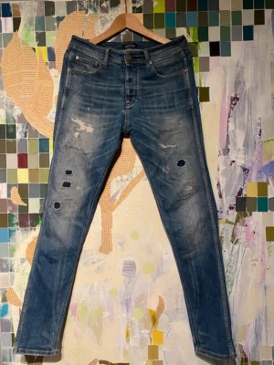 Blå slitna slim jeans  - Säljer ett par blå skinny jeans med slitningar och hål på båda benen. Riktigt fräscha jeans från Jack & Jones.    10/10 skick. Hör av er för mer funderingar 👏🙌.        Storlek W 30 L 34
