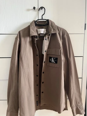 Calvin Klein skjorta - Stilren beige skjorta från Calvin Klein Jeans, ny med prislapp kvar. Storlek M