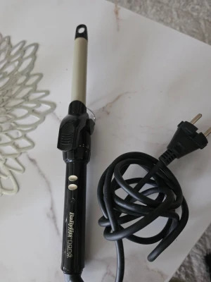 Locktång från BaByliss Nano - Säljer en svart och silver locktång från BaByliss Nano med sladd och EU-kontakt. Perfekt för att skapa snygga lockar och vågor i håret. Enkel att använda med två knappar på handtaget och ett smalt värmeelement.