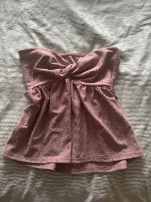Rosa tubtopp med volang - Söt rosa tubtopp med spetsdetaljer. Toppen har en lätt utsvängd passform och är perfekt för sommaren. Passar XS/S