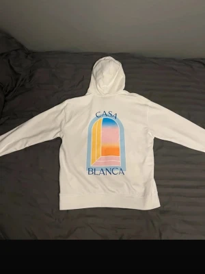 Vit hoodie med Casa Blanca tryck - Casa blanca hoddie  Beskrivning  En stilren vit hoodie från Casa Blanca med snyggt färgglatt tryck på bröstet. Mjukt material som känns skönt att ha på sig.  Detaljer:  * Märke: Casa Blanca * Storlek: M * Färg: Vit * Skick: Mycket bra (inga defekter, fläckar eller noppor)  Pris: 699 kr  Skickas samma dag eller dagen efter📦 