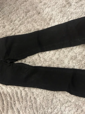 Svarta skinny jeans från Perfect Jeans - Säljer ett par svarta skinny jeans från Perfect Jeans i storlek 34. Jeansen har klassisk femficksmodell, dragkedja och knapp framtill samt hällor för skärp. Snygg passform som sitter tight hela vägen ner.