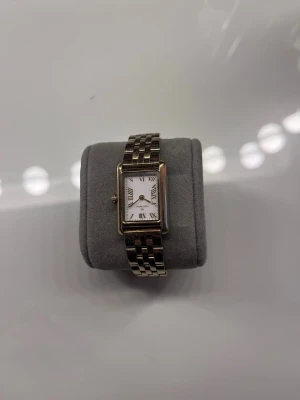 Mockberg klocka - Stilren armbandsklocka med rektangulärt ur i guldfärg och klassisk länkarmband. Urtavlan är vit med romerska siffror och svarta visare. Perfekt accessoar för dig som gillar en tidlös och elegant look. Används därmed fåtal gånger 