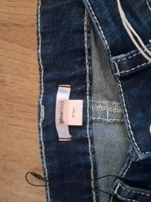 Blå utsvängda jeans Gina Tricot - Säljer ett par blå utsvängda jeans från Gina Tricot med snygga broderade fickor bak. Jeansen har en klassisk femficksmodell och coola detaljer på bakfickorna. Perfekta för dig som gillar retrostil och vill sticka ut lite extra.