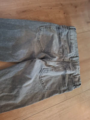 Grå jeans från Gina Tricot - Snygga grå jeans från Gina Tricot i storlek 152. Klassisk femficksmodell med raka ben och normal midja. Jeansen har en cool tvättad look och är tillverkade i mjukt denimtyg som passar perfekt till vardagsstilen.