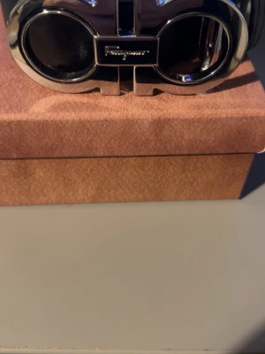 Salvatore Ferragamo svart skärp - Snyggt svart bälte från Salvatore Ferragamo med en ikonisk, glänsande silverfärgad spänne.                  Skriv för mer info! Först till kvarn 