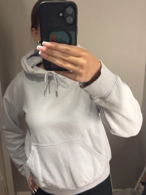 Ljusblå hoodie med huva - Säljer en enkel och stilren ljusblå hoodie med huva. Hoodien har en klassisk känguruficka framtill och ribbade muddar vid ärmar och nederkant. Använd ett fåtal gånger 