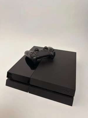 PlayStation 4 spelkonsol med handkontroll - Säljer en svart PlayStation 4 spelkonsol från Sony med tillhörande svart DualShock 4-handkontroll. Konsolen är nyrenoverad och intärn tvättad!