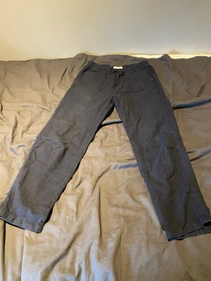 Mörkblå linnebyxor från Lindex - Snygga mörkblå linnebyxor från Lindex i rak modell med resår i midjan och dragsko. Byxorna är tillverkade i ett lätt och luftigt linnetyg, perfekta för en avslappnad och stilren look.