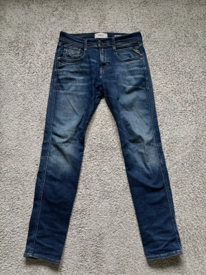 Blå Replay Hyperflex Anbass jeans - Säljer ett par blå Replay Hyperflex Anbass jeans slim fit i storlek 29/32. Moddelen är 178 och sitter väldigt bra. Mjukt material så går lätt att töja. Kom privat vid minsta lilla och pris går givetvis att diskutera🍾🍾