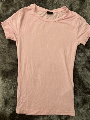 Ljusrosa basic t-shirt - En enkel och stilren ljusrosa t-shirt med rund hals och korta ärmar. T-shirten är i mjuk bomull och har en normal passform, perfekt för en avslappnad look. Passar till allt och är ett måste i garderoben.