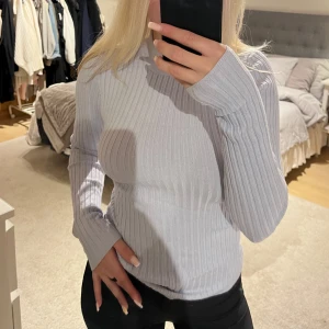 Ljuslila/blå ribbad tröja från Gina Tricot - Supersnygg ljuslila/blå ribbad tröja från Gina Tricot med långa ärmar. Tröjan är figurnära och har en stilren look som passar perfekt till jeans eller kjol. Materialet är mjukt och stretchigt för extra komfort.