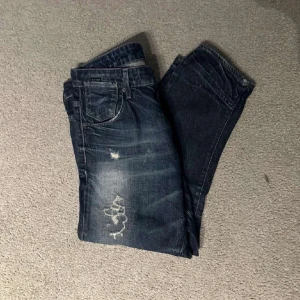 Mörkblå G-star jeans med slitningar - Tja! Säljer dessa snygga mörkblåa G-star jeans med feta slitningar i storlek 31/32. Jeansen är i bra skick och har inga defekter, skicket är 9/10. De är midja 31 men skulle säga att den nästan passar som en 32 också och rekommenderad längd sitter på något runt 180. Tveka inte att att höra av dig vid frågor och funderingar! 