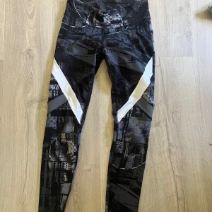Svarta Reebok leggings med mönster - Snygga svarta leggings från Reebok med grått och vitt grafiskt mönster. De har hög midja. Storlek står ej men skulle säga S