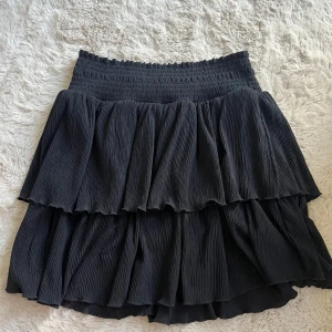 Svart volangkjol från Kappahl - Supersöt svart kjol med mycket stretch i midjan. Kommer från Kappahl i strl 170💘 Använd men inga stor tecken på användning!