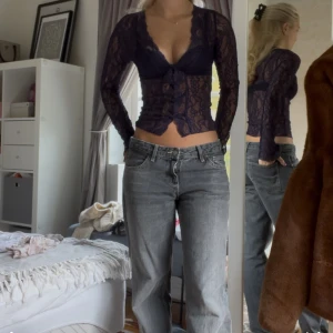 Mörkblå spetsblus med knappar - Säljer en mörkblå, transparent spetsblus med djup v-ringning och långa ärmar. Blusen är croppad och har dekorativa knappar framtill. Perfekt för dig som gillar romantiska detaljer och vill sticka ut lite extra.