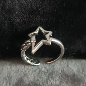 Stjärnring i äkta silver 925 - Cool och unik ring i äkta silver 925 med en öppen design och en stjärnformad detalj framtill. Ena sidan av ringen har ett flätat mönster som ger extra edge. Perfekt för dig som gillar statement-smycken med lite extra attityd.