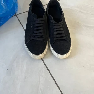 Axel arrigaro skor  - Snygga svarta sneakers från Axel Arigato i mocka med klassisk snörning och vit platt sula. Perfekt för dig som gillar stilrena och minimalistiska skor med en modern touch. Passar till både jeans och dressade outfits. Pris går att diskutera, hör av dig vid frågor eller bilder. 