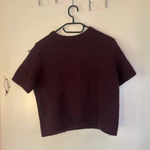 Mörklila stickad tröja Gina Tricot - Kortärmad, vinröd stickad tröja från Gina Tricot. Tröjan har en rund halsringning med ribbad kant och är i en mjuk, mysig stickad kvalitet. Perfekt för lager-på-lager och passar till både jeans och kjol.