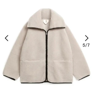 Beige teddyjacka med dragkedja - Säljer en beige teddyjacka med svart kant och dragkedja framtill. Jackan har två stora fickor och en bred krage som ger en chill vibe. Perfekt för kalla dagar när du vill vara både varm och snygg.