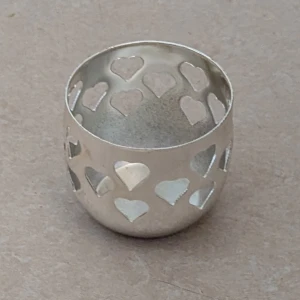 Ljushållare med hjärtmönster - Ljushållare i silverfärgad metall med utskurna hjärtan runt hela ljushållaren Ljushållaren kan även användas som dekoration. Det finns några små repor i botten på insidan av ljushållaren ( syns på bild ).