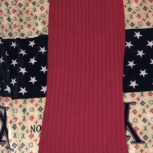 Röd ribbad kjol - Säljer en röd ribbad kjol med enkel och stilren design. Kjolen har en tight passform och är tillverkad i ett mjukt, stretchigt material som sitter snyggt på kroppen. Perfekt för dig som gillar minimalistisk stil och vill ha något som sticker ut med sin färg.