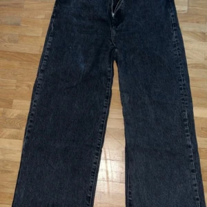 Svarta wide jeans från 157, stl S - Säljer ett par svarta jeans från 157 i storlek S. Jeansen har en rak och bred passform med klassisk femficksdesign, dragkedja och knapp framtill. Materialet är denim och färgen är tvättad svart för en cool look.