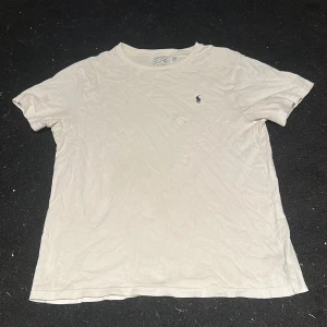 Vit t-shirt från Ralph Lauren - Vit t-shirt från Ralph Lauren med klassisk rund hals och korta ärmar. Diskret Polo-logga broderad på bröstet. Mjuk och skön bomull som passar perfekt till jeans eller shorts. Enkel och stilren design för en chill look.