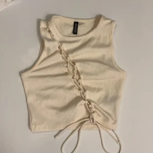 Vit ribbad linnetopp från H&M  - Säljer en vit ribbad linnetopp från H&M Divided i storlek XXS passar även XS. Toppen är croppad och har en snygg snörning diagonalt framtill. 