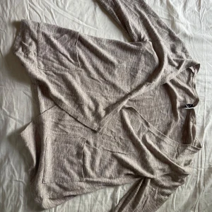 Beige omlottkofta från Freequent - Säljer en beige omlottkofta från Freequent i mjukt, tunt material. Koftan har långa ärmar, två stora fickor framtill och en avslappnad passform. Perfekt för lager-på-lager och chill dagar. Passar dig som gillar en enkel och stilren look.