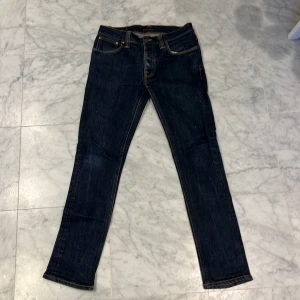 Mörkblå jeans från Nudie Jeans Co - Tvärfeta mörkblå nudie jeans i modellen ”grim Tim”. Byxorna är omsydda och sitter som W30 och L32