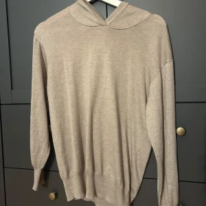 Beige hoodie från Ellos med huva - Snygg beige hoodie från Ellos i mjukt stickat material. Tröjan har långärmad design, ribbade muddar och en stilren huva. Perfekt för dig som gillar en enkel och clean look med en chill vibe.