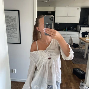 Vit blus med spets från Odd Molly - Superfin vit blus från Odd Molly med romantiska spetsdetaljer, broderade blommor och liten rosett framtill. Blusen är luftig med lös passform och långa ärmar, perfekt för en chill och bohemisk vibe. Materialet känns lätt och svalt mot huden.