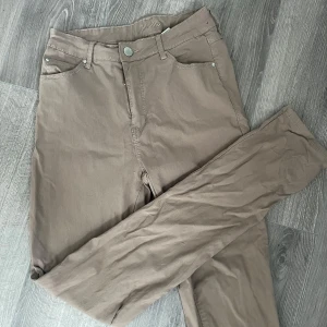 Beige slim chinos från Holly & Whyte - Snygga beige chinos från Holly & Whyte i storlek 38N. Byxorna har klassisk femficksdesign, smal passform och är tillverkade i mjuk bomullsmix. Perfekta för dig som gillar stilrena och bekväma byxor med en clean look.