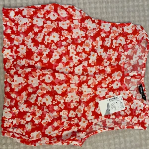 Blommig topp - Superfin blommig topp i rött, vitt och rosa. Ärmlös modell med rund halsringning och liten knapp i nacken. Tunt och luftigt material. Aldrig använt den.