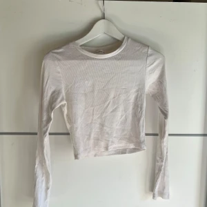Vit croppad långärmad tröja Even&Odd - Vit croppad långärmad tröja från Even&Odd. Tröjan är ribbad och har en enkel, stilren design med rund halsringning. Perfekt att matcha med höga jeans eller kjol för en clean look.
