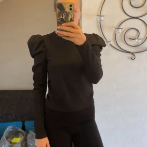 Svart topp med puffärmar Pull&Bear - Svart långärmad topp från Pull&Bear med trendiga puffärmar som ger en snygg siluett. Enkel rund halsringning och figurnära passform. Perfekt för dig som vill ha en stilren men ändå statement look. Storlek M men ganska liten i storlek så passar absolut S och XS💕