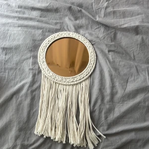 ENERGISKOG - Unik väggdekoration med spegel och makramé-inspirerade fransar. Perfekt för att ge ditt rum en bohemisk och trendig känsla. Passar utmärkt i sovrum, vardagsrum eller hall för en personlig touch. Mått: 26x48 cm.