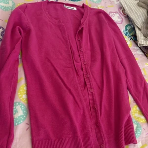 Rosa kofta från Porta Fortuna S/M - Snygg rosa kofta från Porta Fortuna i storlek S/M. Koftan har långa ärmar, rund halsringning och knappar framtill. Materialet känns mjukt och lätt, perfekt att slänga över en t-shirt eller linne. Enkel och stilren design som passar till många outfits.