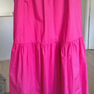 Chockrosa långklänning från H&M XS - En riktigt snygg chockrosa långklänning från H&M i 100% bomull. Klänningen har en voluminös och luftig passform med rynkade sömmar och enkel design. Perfekt för dig som vill sticka ut med färg och gillar bekväma plagg.